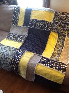 a couch with a yellow and black patchwork blanket on it's back next to a window