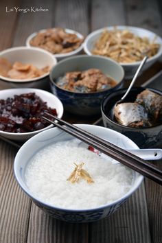 there are many bowls of food on the table with chopsticks in each bowl