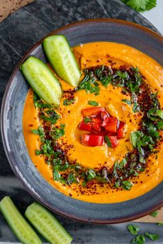 a bowl filled with hummus and garnishes on top of a table