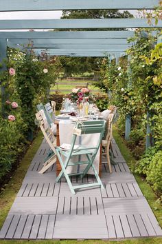 an outdoor dining area with blue and white chairs, tables and flowers on the table