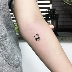 a small black and white cat tattoo on the left inner arm by an unknown person