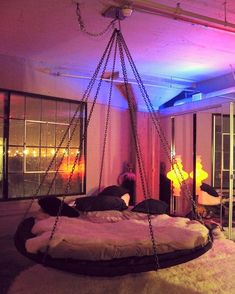 a bedroom with a swing bed in the middle and purple lights on the ceiling above it