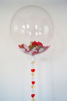 a clear balloon with red, white and gold confetti on it's side