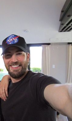 a man and woman taking a selfie in front of a window with their arms around each other