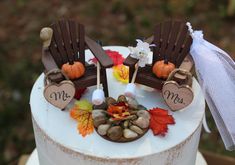 a wedding cake decorated with two chairs and fall leaves