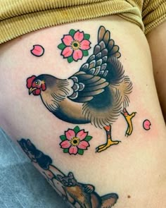 a woman's thigh with a rooster and flowers on her side, tattoo style