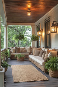 a porch with couches and potted plants on the front steps, lights hanging from the ceiling