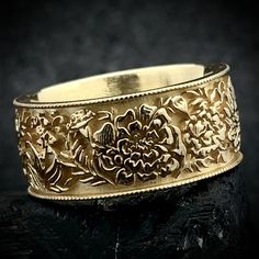 a close up of a gold ring with flowers on it's sides and an intricate design