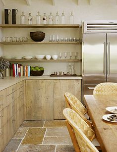 a kitchen filled with lots of wooden cabinets and counter top space next to a dining room table