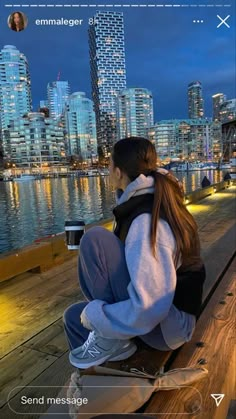 a person sitting on a bench looking at the water and buildings in the city behind them