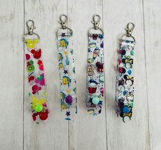 three keychains with different designs on them sitting on a white wooden floor next to each other