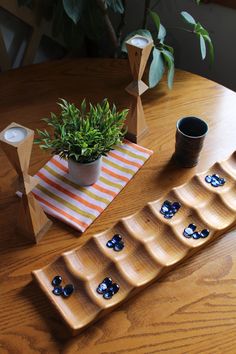 a wooden table topped with two trays filled with blue flowers and small pots on top of it