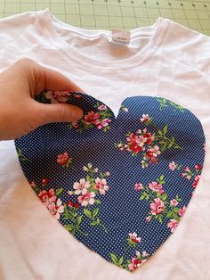 a heart shaped t - shirt being sewn by someone's hand on a sewing machine