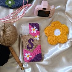 some crocheted items are laying out on a white sheet next to yarn and a camera