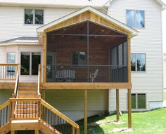 a house with a screened porch on the front and second story in the back yard