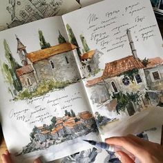 a person holding a pen and writing on paper with watercolors in front of them