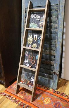 an old wooden ladder stands in front of a door with earrings on it and a rug