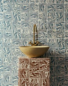 a bathroom sink sitting on top of a tiled counter next to a wall mounted faucet