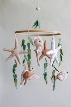 a crocheted mobile with sea animals hanging from it's sides and green leaves