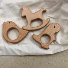 three wooden toy animals sitting on top of a white cloth next to a pair of scissors