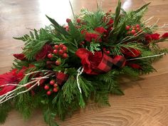 a christmas arrangement with red flowers and greenery