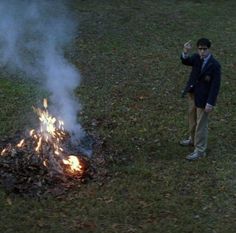 a man standing next to a fire in the grass