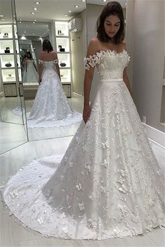 a woman standing in front of a mirror wearing a wedding dress with flowers on it