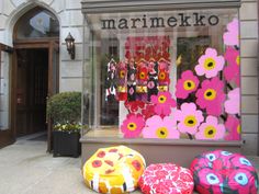 three brightly colored bean bags sitting in front of a store window with flowers painted on it