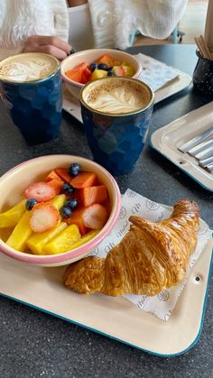 there is a croissant, fruit and coffee on the table at this restaurant