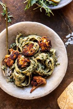 a white bowl filled with pasta covered in pesto sauce