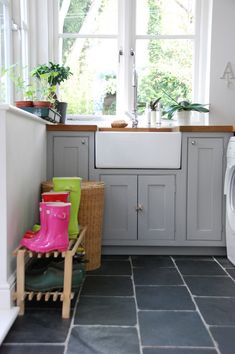 a kitchen with grey cabinets and tile flooring next to a white washer and dryer