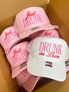 pink hats with just drunk in love written on the front and back are sitting in a cardboard box