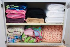 an open cabinet filled with lots of folded towels and cloths on top of each other