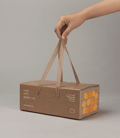 a hand is holding a brown box with orange designs on it and the bottom half has a handle