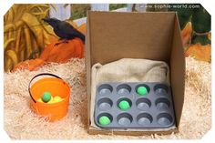 an orange bucket with green balls in it next to a cardboard box filled with eggs