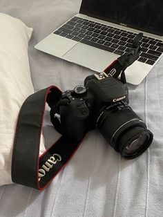 a laptop computer sitting on top of a bed next to a camera