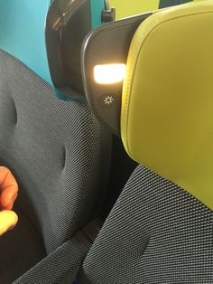 a person is sitting in a seat with their hand on the arm rest and holding something