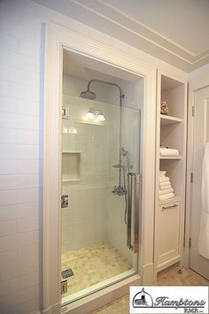 an instagramted photo of a bathroom with the shower stall door open and shelves full of towels