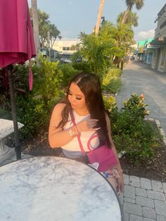 a woman sitting at an outdoor table with her hand on her shoulder and looking down