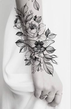 a woman's arm with flowers and leaves on it