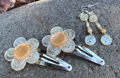 three pairs of scissors are laying on the ground next to some buttons and earring clips