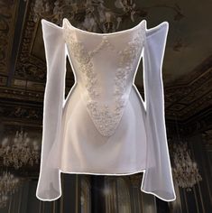 the back of a white wedding dress on display in a room with chandeliers