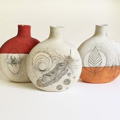 three vases with designs painted on them are lined up against a white background,