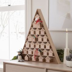 a christmas tree made out of wooden blocks on top of a dresser next to a window