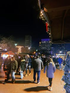 many people are walking around in the city at night with their lights on and buildings lit up behind them