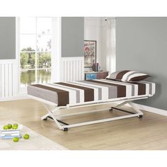 a bed sitting on top of a wooden floor next to a white table and chair