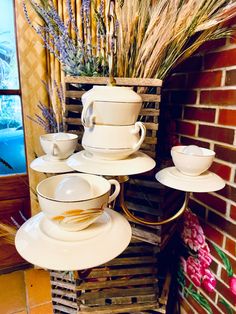 a stack of white dishes sitting on top of a wooden crate next to a brick wall