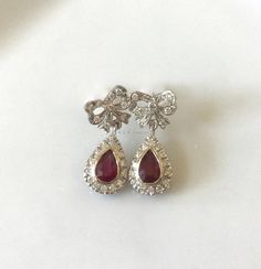 Metal: 14kt White Gold Stone: Diamond And Ruby Shape: Round And Pear-shape Ruby Weight : 1.00 ctw Diamond Weight: .52 ctw Type Of Backing: Post Weight of entire piece: 5.60 grams Dimensions of Earrings From Top To Bottom: 24.22mm Customizable: We can custom make these earrings (and its matching necklace) with any gems and metals of your choice. Please inquire if interested. Matching Necklace: https://www.etsy.com/listing/549448744/vintage-style-14k-white-gold-ruby-and?ref=shop_home_active_2 Platinum Gemstone Jewelry For Evening, Pear-shaped Gemstone Jewelry For Evening, Sapphire Diamond Earrings For Anniversary, Luxury Hallmarked Pear-shaped Diamond Earrings, Luxury Pear-shaped Diamond Earrings With Gemstones, Luxury Pear-shaped Gemstone Diamond Earrings, Elegant Teardrop Diamond Earrings Hallmarked, Vintage Teardrop Diamond Jewelry, Elegant Oval Diamond Earrings With 17 Jewels