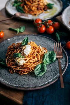 two plates with spaghetti and tomatoes on them