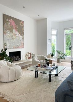 a living room filled with furniture and a large painting on the wall above the fireplace